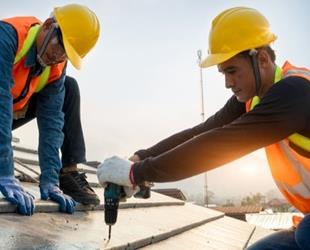 Two people in helmets working on a roof.