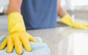 A cleaning professional wipes the counter clean at their client's Airbnb house