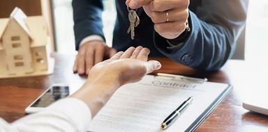 Real estate professional handing keys to home owner.