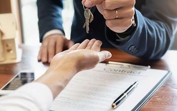 Real estate professional handing keys to home owner.