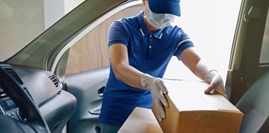 Medical courier loading secure package into car for delivery.