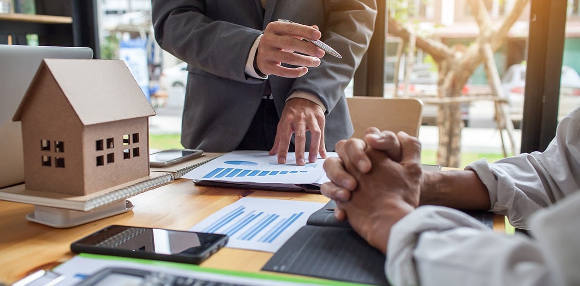 Business professionals discussing real estate investment with charts Business professionals discussing real estate investment with charts