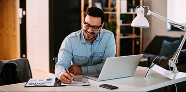 Insurance agent working at home with laptop and papers.