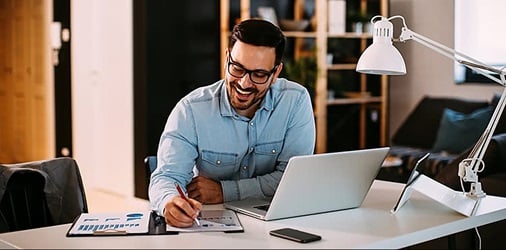 Insurance agent working at home with laptop and papers.