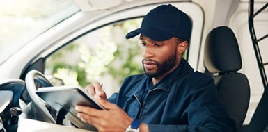 Driver filling out details on tablet in van to deliver a package.