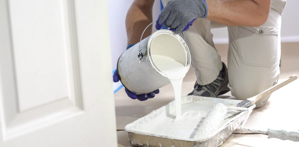 Painter pouring paint from a can into a paint tray. Painter pouring paint from a can into a paint tray.