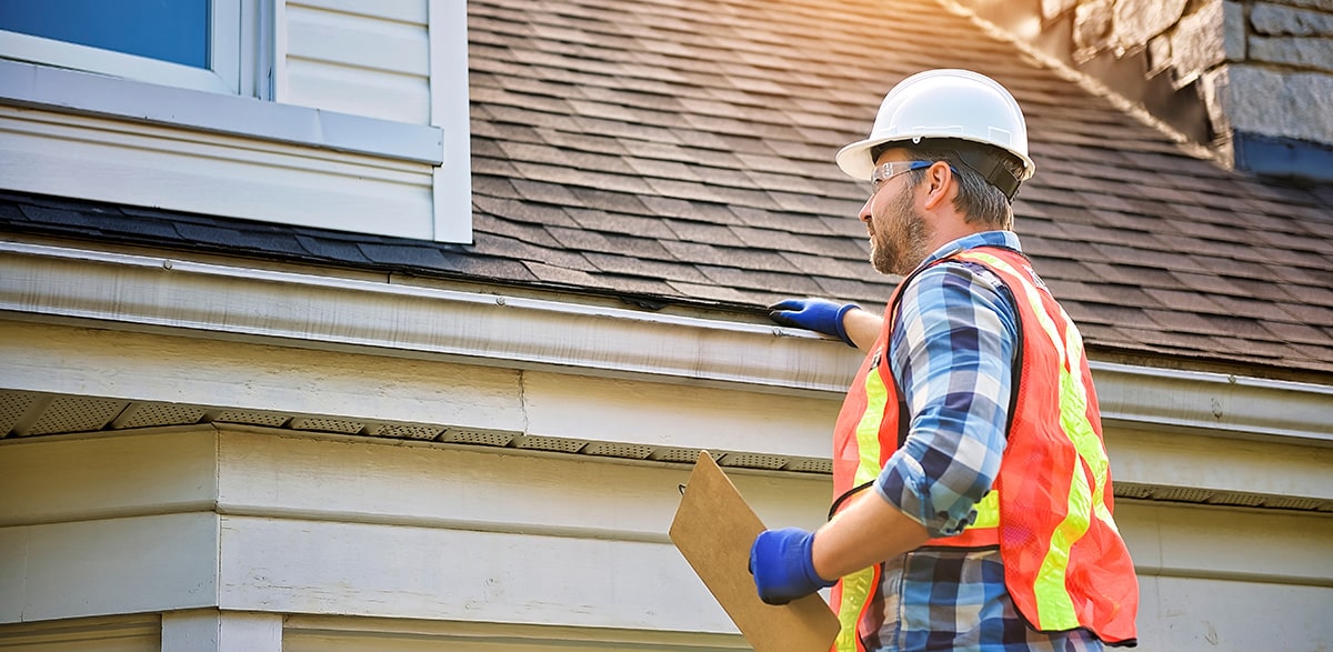 Contractor inspecting roof for damage.
