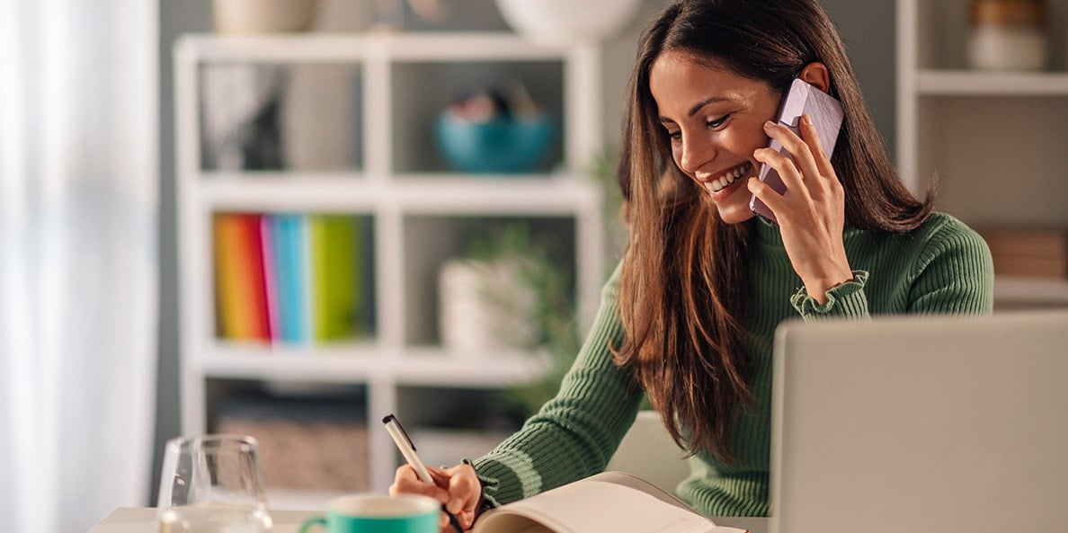 Person on the phone taking notes in a home office. Person on the phone taking notes in a home office.