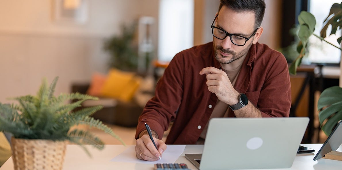 Writing notes while working on laptop at home office. Writing notes while working on laptop at home office.
