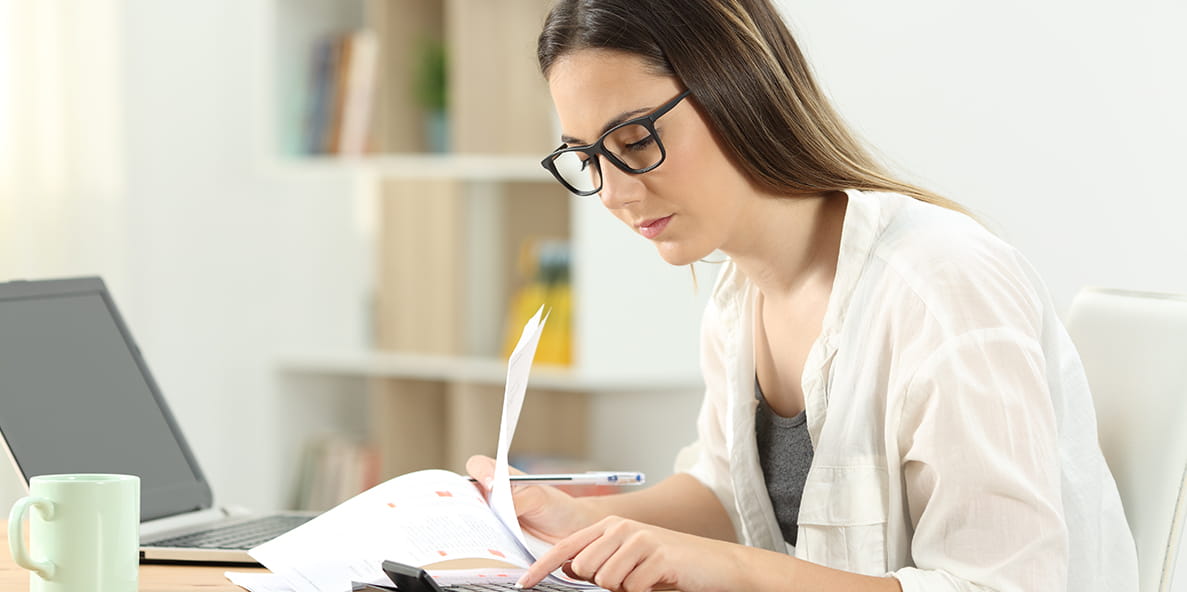 Person studying at a desk with a laptop, papers, and a calculator. Person studying at a desk with a laptop, papers, and a calculator.