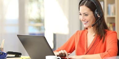 Person wearing a headset working on a laptop.