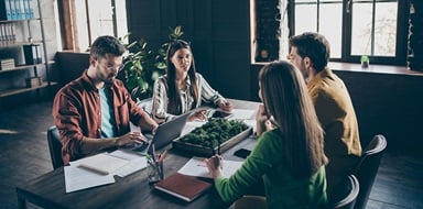 Four colleagues having a meeting around a table in a office.