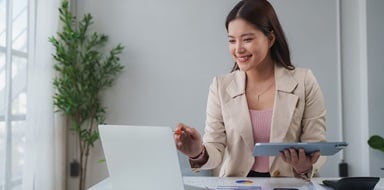 A businesswoman working on laptop and tablet at desk.