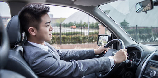 Businessman in a gray suit driving a car.