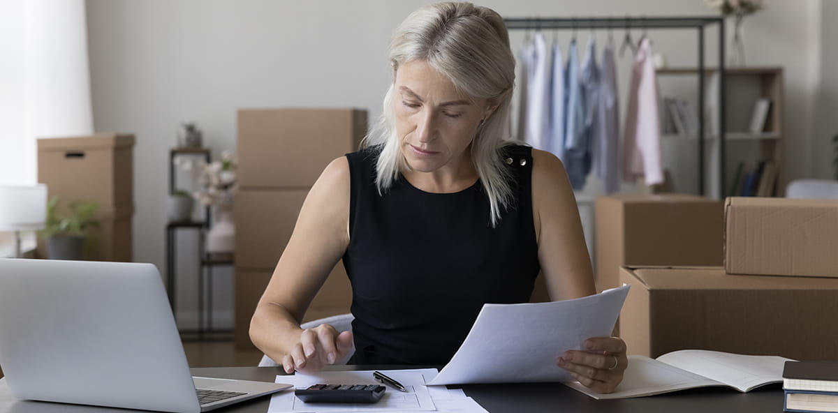 Person reviewing tax deduction documents in front of a laptop. Person reviewing tax deduction documents in front of a laptop.