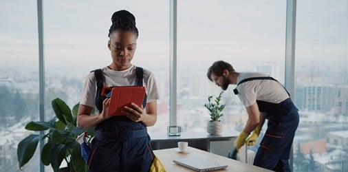 Office cleaners using a tablet while cleaning a workspace.