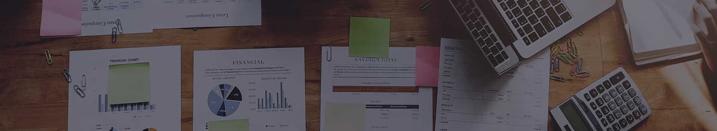 An accountant's desk full of cost sheets and a calculator.