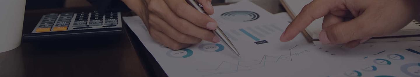 Financial advisors at a desk looking at cost tables. Financial advisors at a desk looking at cost tables.