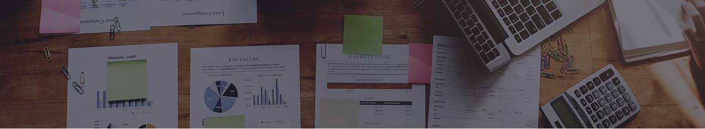 An accountant's desk full of cost sheets and a calculator.