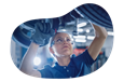 Mechanic working underneath a car at an auto body shop.