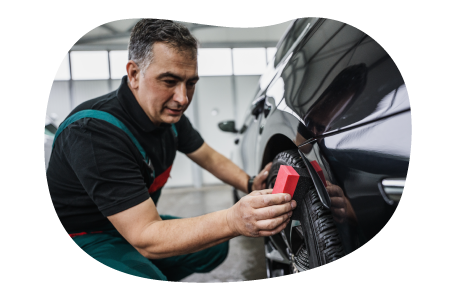 Auto shop employee detailing a car.