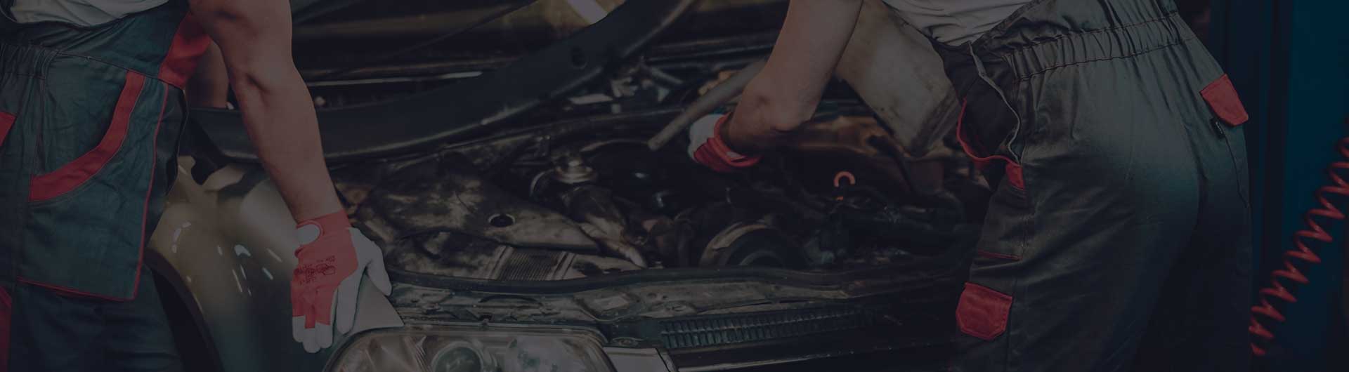 Two mechanics fixing car in a workshop.