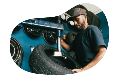 Tire shop employee working on a customer's car. Tire shop employee working on a customer's car.