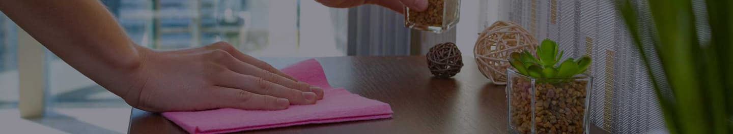Person dusting a side table with a pink cloth. Person dusting a side table with a pink cloth.