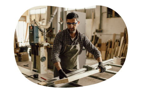 Carpenter moving wood planks in workshop.