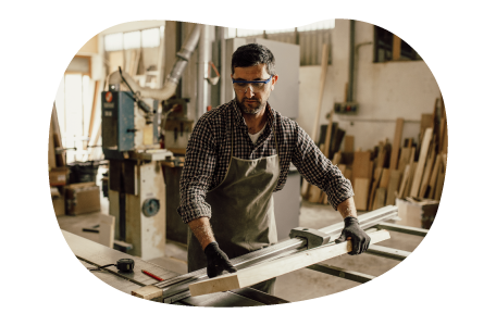 Carpenter moving wood planks in workshop.