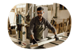 Carpenter moving wood planks in workshop.