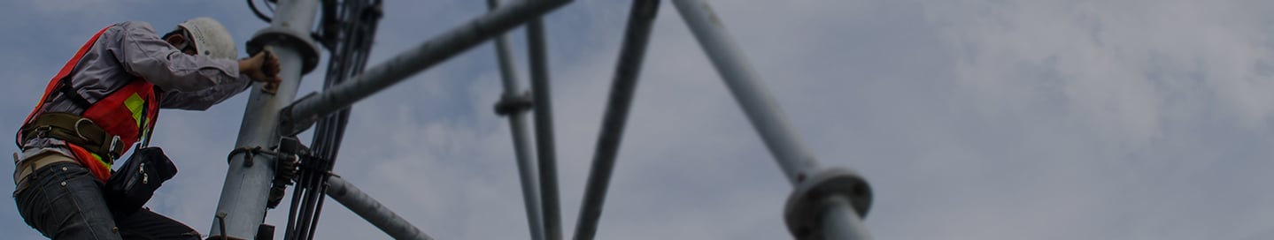 A cell tower technician climbs down after completing a job. A cell tower technician climbs down after completing a job.