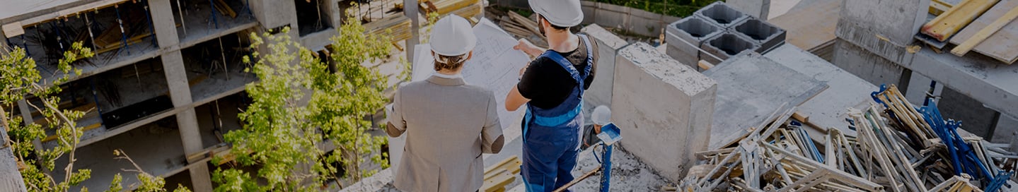 Two commercial builders looking down on a structure in progress. Two commercial builders looking down on a structure in progress.