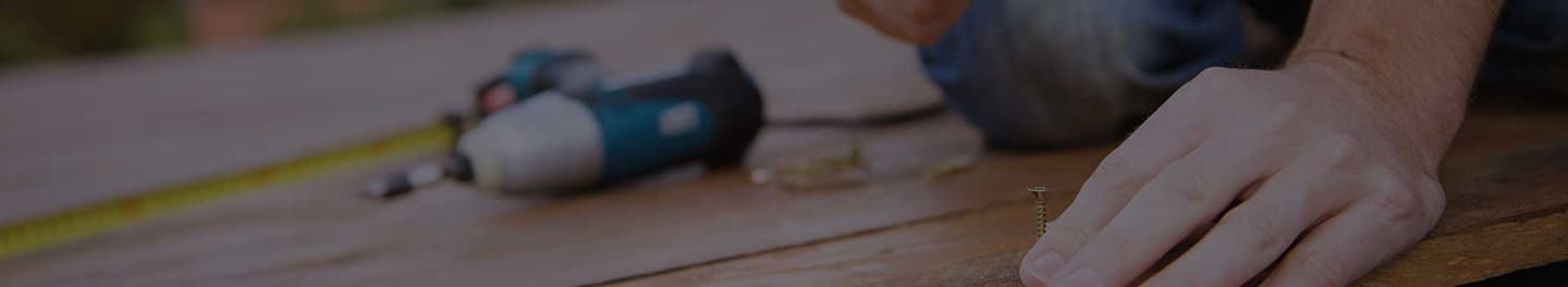 Handyman putting a screw into a deck.