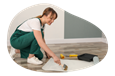 A paperhanging contractor applies adhesive to the back of wallpaper.
