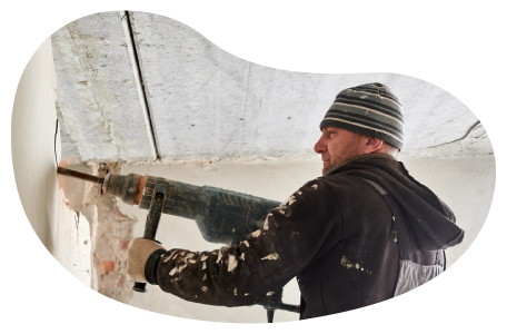 A restoration contractor uses a demolition hammer on a wall.