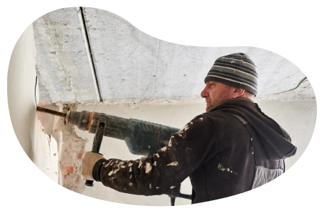 A restoration contractor uses a demolition hammer on a wall. A restoration contractor uses a demolition hammer on a wall.