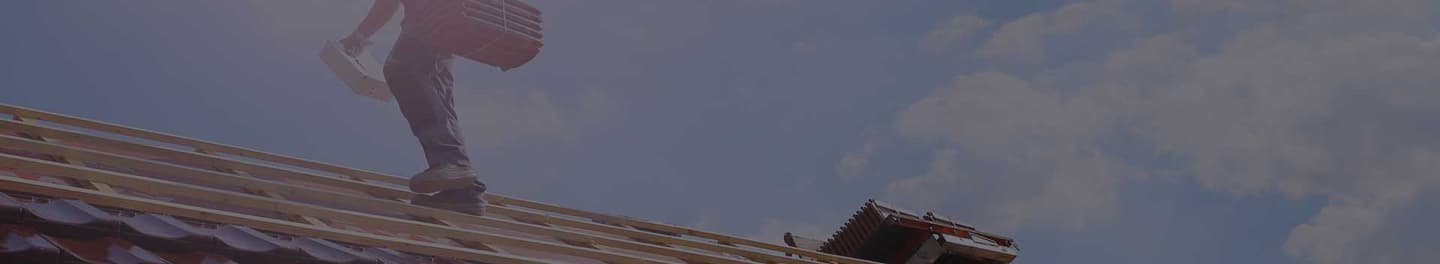 A roofer tiling the roof of a house A roofer tiling the roof of a house