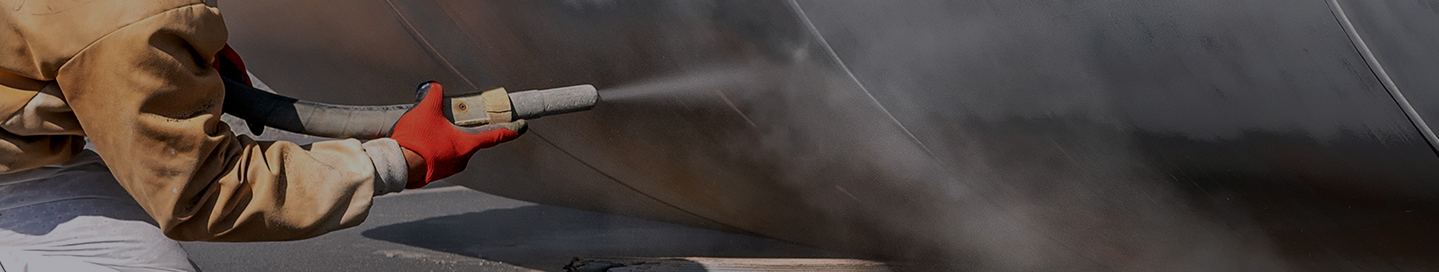 A sandblasting contractor cleans a metal surface.