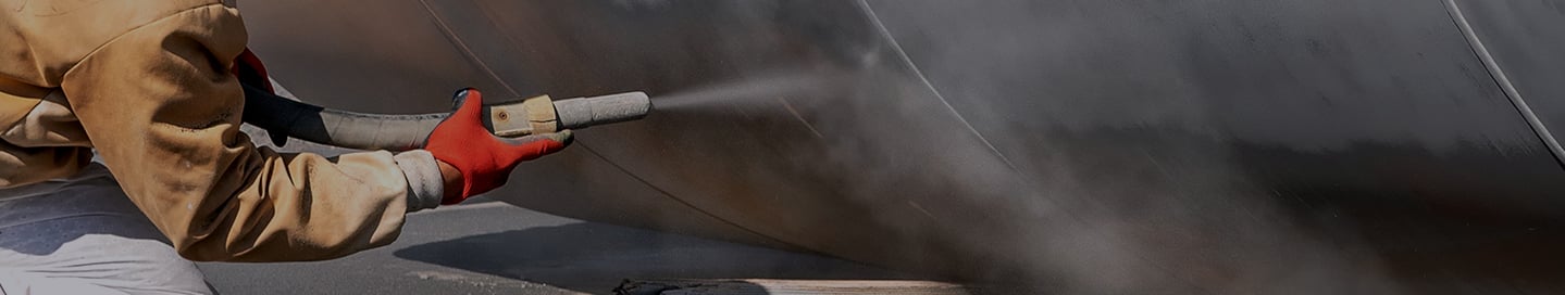A sandblasting contractor cleans a metal surface. A sandblasting contractor cleans a metal surface.