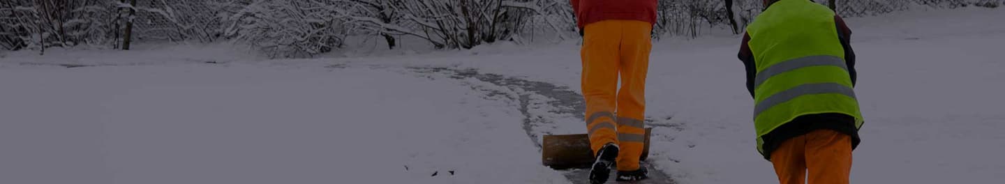 Two men removing snow in a park Two men removing snow in a park
