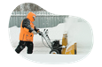 Snow removal professional plowing a sidewalk.