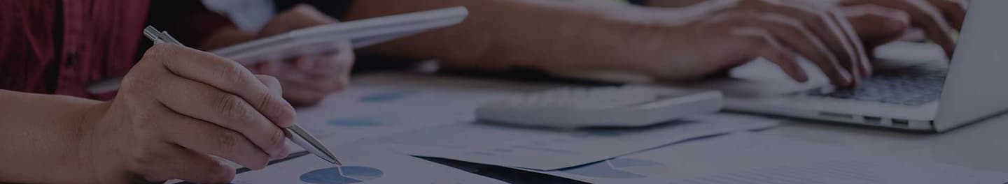 Two consultants at a desk with a laptop and paperwork.