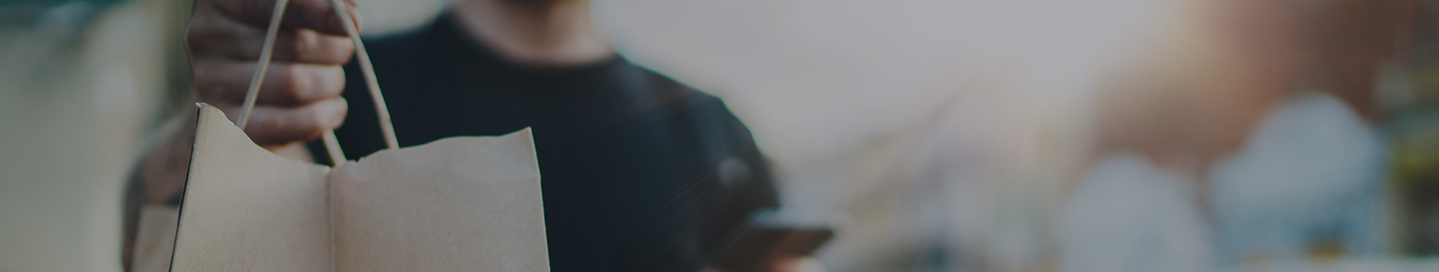 A DoorDash driver delivers a meal in a brown paper bag.