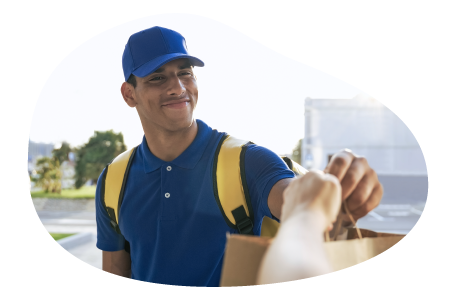 A Grubhub driver hands a meal to a customer.