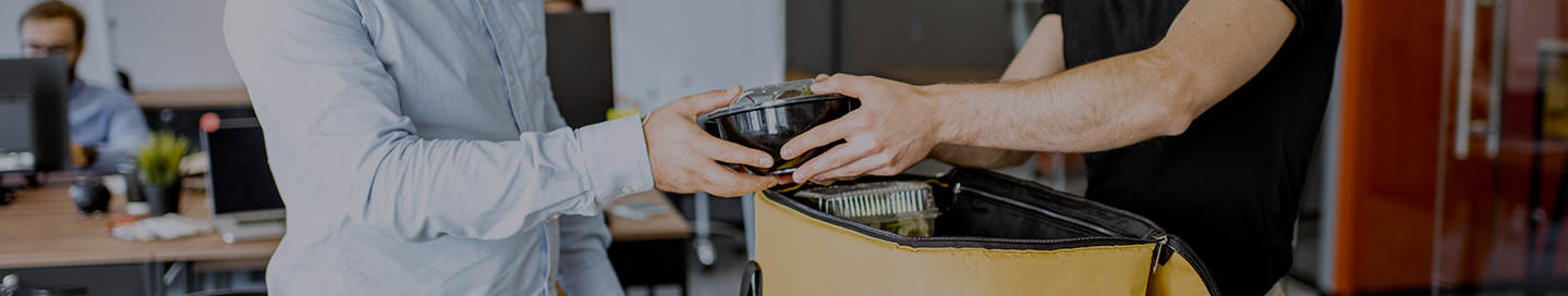 A delivery driver hands a customer their takeout meal.