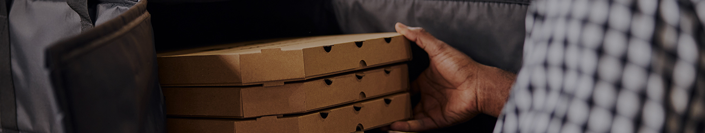A delivery driver stores pizzas in their insulated delivery bag.