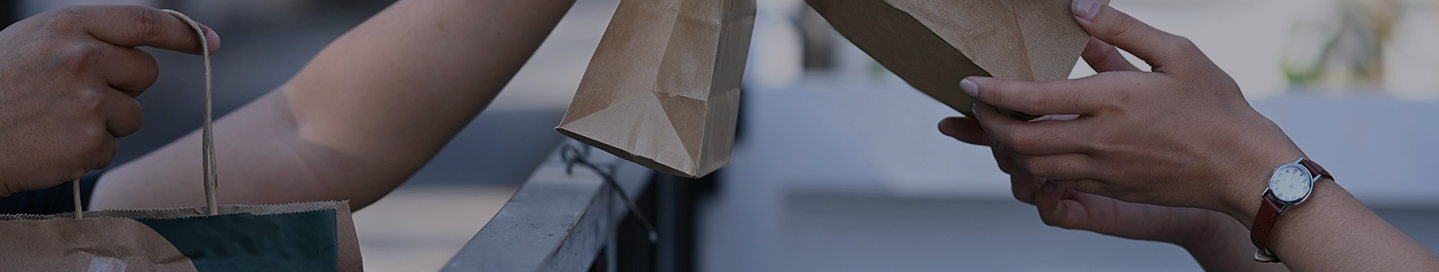 An Uber Eats driver hands a meal to a customer.
