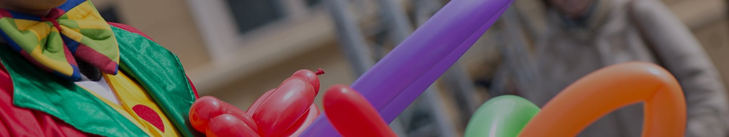A clown creates balloon art for an audience. A clown creates balloon art for an audience.