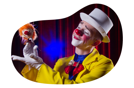 A clown in a yellow suit performs with a puppet.